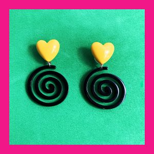 Pendiente con espiral negra y corazón amarillo.